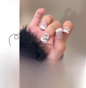 Detail of French white press-on nails with silver lines and heart rhinestone accents