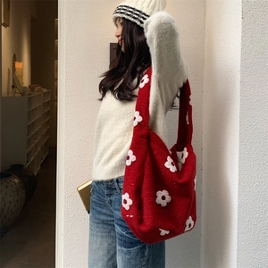 Detailed texture of red knitted tote bag with 3D white floral embellishments for winter