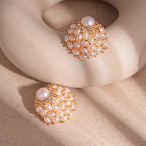 Detailed close-up of golden pearl earrings with vintage clusters and crystals