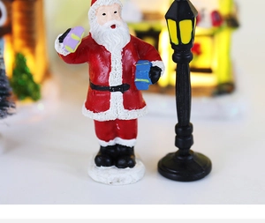 Close-up of resin Santa Claus miniature with gift box and European style black street lamp