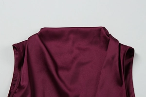 Detailed view of burgundy satin dress showing elegant cowl neck and silky fabric texture