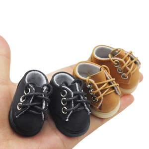 Close-up of miniature 20cm doll shoes in black and brown finish with rubber soles