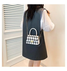 Détail du sac en tweed à carreaux avec chaîne dorée et poignée blanche élégante