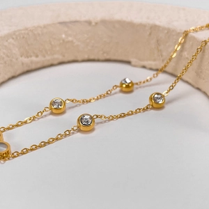 Macro detail of golden chain necklace with bezel-set round clear cubic zirconia stones