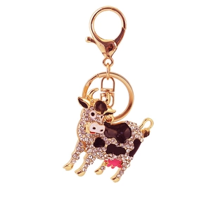 Sparkling gold metal cow keychain with white and black enamel and clear crystal rhinestones