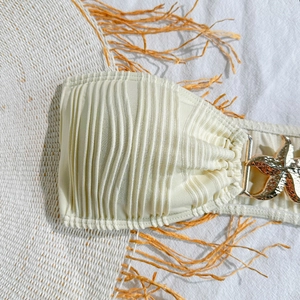 Detail of starfish metal buckle on cream pleated bikini with beach holiday hat