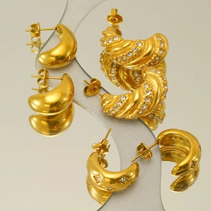 Golden titanium steel hoop earring set with twisted and star patterns on a mirror