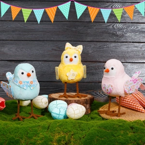 Three Easter fabric bird figurines in blue, yellow and pink on moss and wood