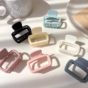 Flat lay of eight matte square claw clips in assorted cream and pastel colors for women