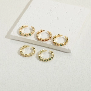Detailed macro view of five adjustable gold rings with vibrant multi-colored gemstones