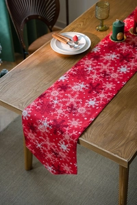 Close-up of red Christmas table runner with snowflake prints on a wooden dining table