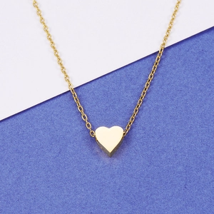 Detailed close-up of a polished gold heart pendant with a fine O-chain on contrast background