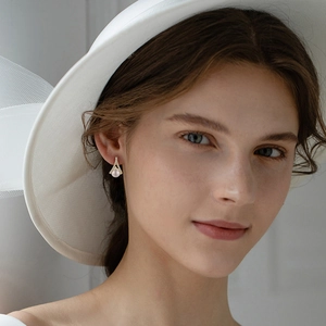 Elegant gold geometric pearl earrings with shimmering diamonds shown on model