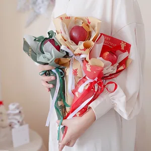 Handheld Christmas apple bouquet wrapped in festive Kraft paper with red ribbons
