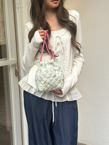 Detail of light green quilted storage bag with floral pattern and pink drawstring handles