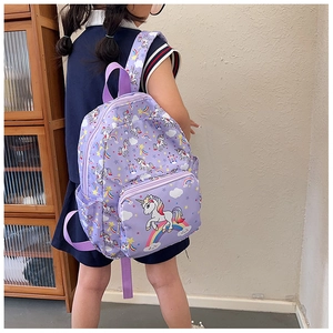 Toddler girl wearing a purple unicorn backpack with rainbow and stars print for travel