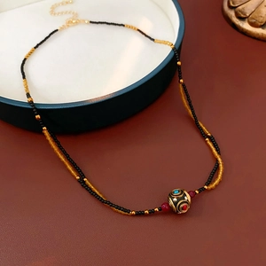 Dettaglio della collana a doppio strato di perline con ciondolo e chiusura dorata