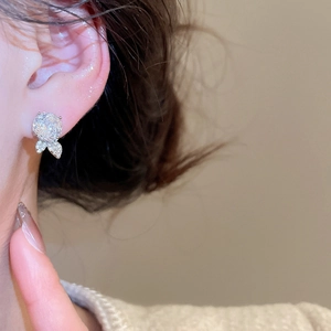 Nahaufnahme von funkelnden Rosen-Ohrsteckern in Silber mit Zirkonia am Ohr getragen