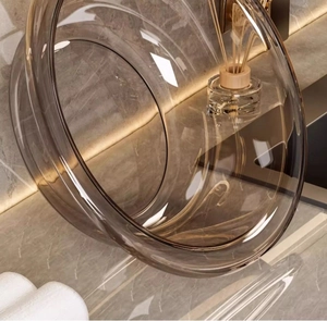 Close-up of an amber transparent plastic washbasin on a grey marble bathroom vanity