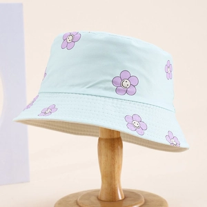 Close-up of light blue kids sun hat with purple smiley flower print and neat stitching