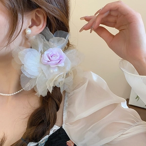 Gros plan d'une pince à cheveux avec roses lavande, pétales de dentelle et perles