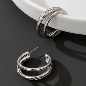 Close-up of silver triple-layered metal hoop earrings with a minimalist geometric design