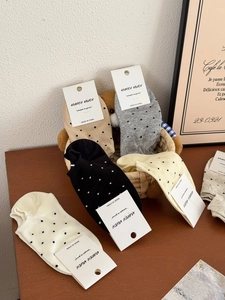 Détail macro de chaussettes en coton à pois dans un panier tressé sur table en bois