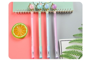 Close-up of cute globe-topped gel pens in pastel colors on a styled creative desktop