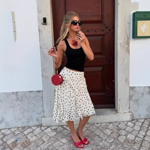 Modischer Polka-Dot-Midirock mit Rüschen, kombiniert mit roter Tasche und schwarzem Top
