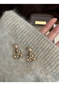 Detail of gold floral earrings with crystal clusters and elegant round faux pearls