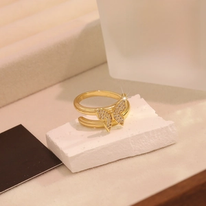 Detailed close-up of a golden double-loop ring with a shimmering zircon butterfly charm