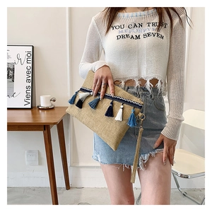 Detail of woven straw clutch bag with blue and white tassels and wrist strap