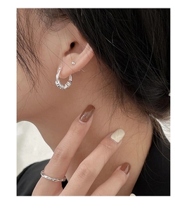 Detail of s925 silver geometric hoop earrings and engraved ring on model's ear and hand