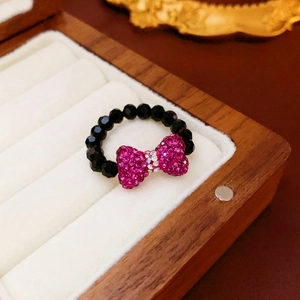 Detail of rose red crystal bow ring with black faceted beads on velvet display