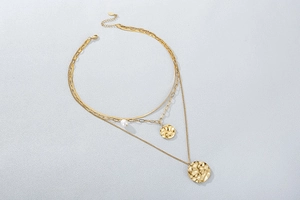Detail of gold layered necklace set with hammer textured pendants and a central pearl
