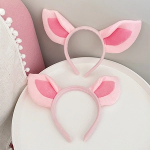 Detail of two pink plush pig ear headbands with soft textures on a clean background