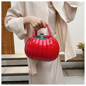 Creative red tomato-shaped handbag with glossy finish and gold chain strap on model
