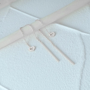 Macro detail of silver S925 heart tassel earrings hanging on a decorative branch