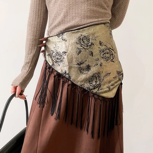 Detail of vintage floral tassel belt with gold metallic finish and black rose pattern