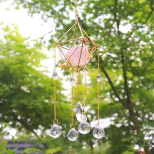 Detail of crystal sun catcher with gold geometric frame and pink quartz prism