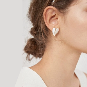 Elegant white enamel heart earrings in gold plated stainless steel on female model