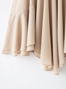Detail of apricot layered chiffon skirt showing fluid drapes and wavy ruffled hemline
