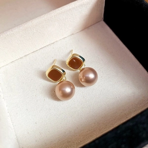 Detail of vintage gold pearl earrings with square enamel inlay in a soft jewelry box