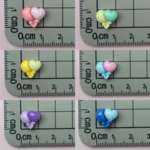Detailed size view of colorful mini resin heart balloon charms on a metric ruler