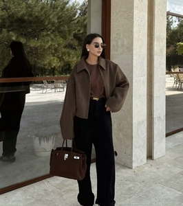 Fashionable brown short wool coat paired with black trousers and leather bag in street style