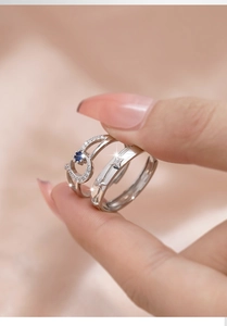 Close-up of 925 silver moon and star couple rings with blue zircon on pink background