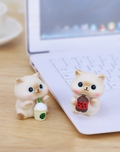 Detail view of cute resin cat figurines holding bubble tea on a wooden office desk