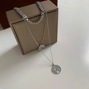 Three-layer silver necklace with tree of life and world map disc pendants set on a display