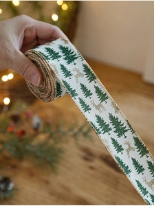 Detail of white Christmas ribbon with green trees and golden glitter reindeer print