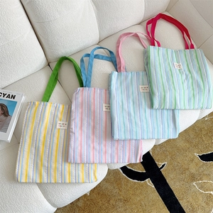 Primo piano di quattro borse tote a righe in colori pastello su un divano bianco